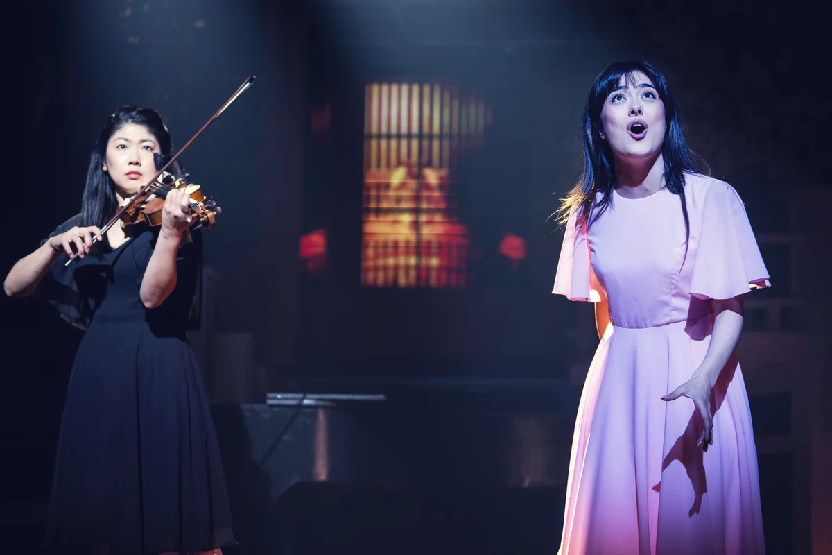 Mia Kobayashi as Kaori in a pink dress singing beside a violinist in Your Lie in April
