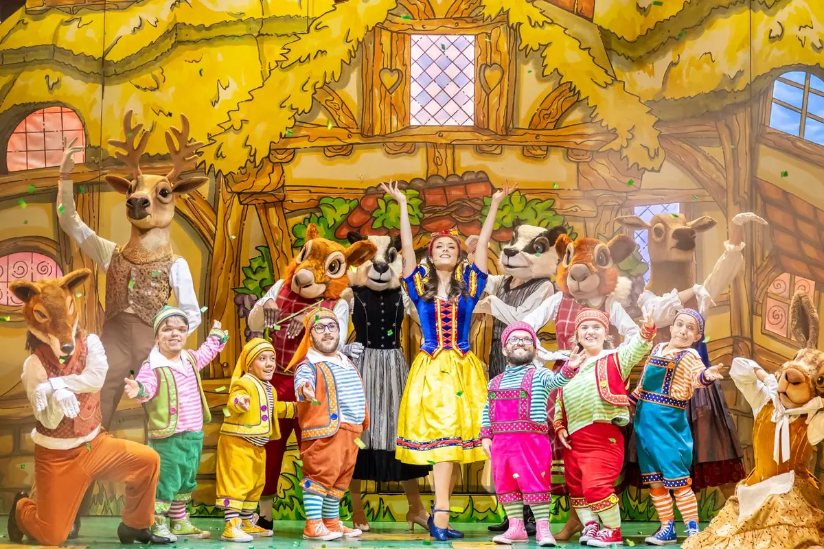 Mia Kobayashi in her Snow White costume surrounded by the seven dwarfs and woodland animals outside the cottage