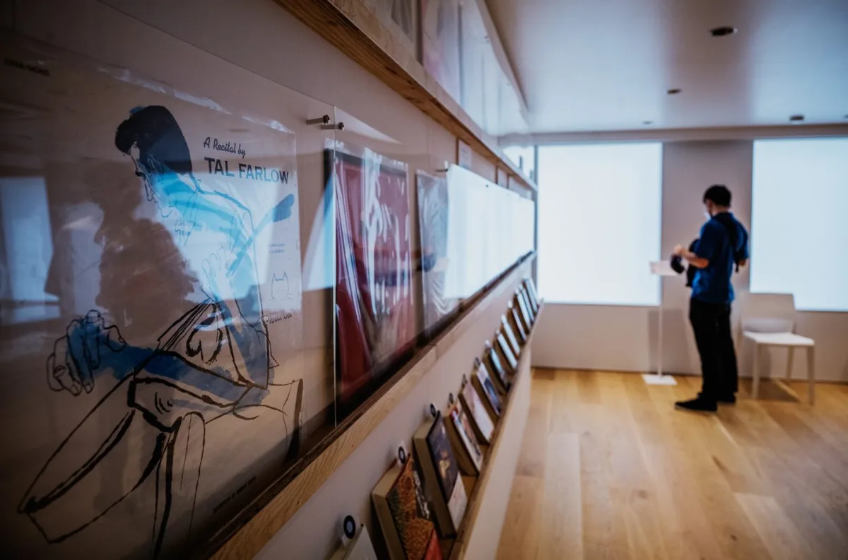 A visitor in the Haruki Murakami Library gallery beside a long shelf of jazz record sleeves, with Tal Farlow's A Recital by Tal Farlow in front