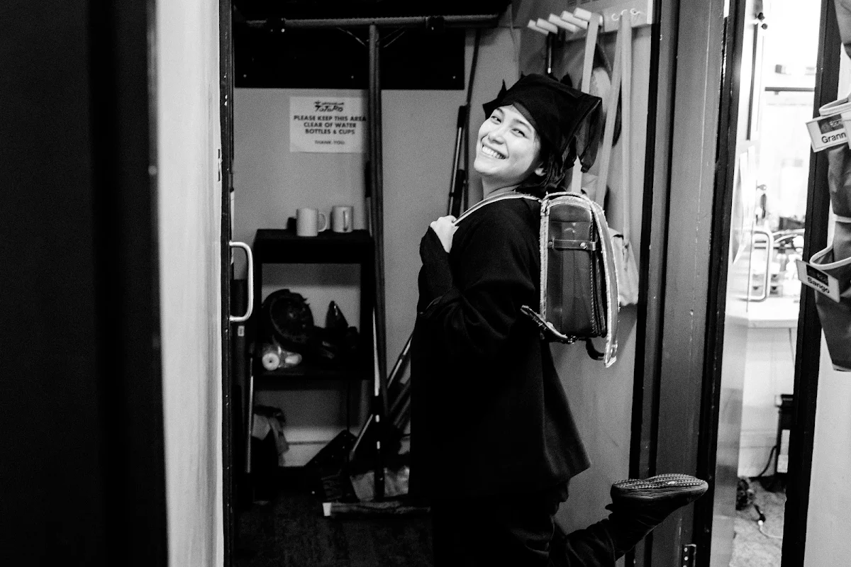 Black and white photograph of Karen Barredo in costume looking back over her shoulder in a backstage doorway