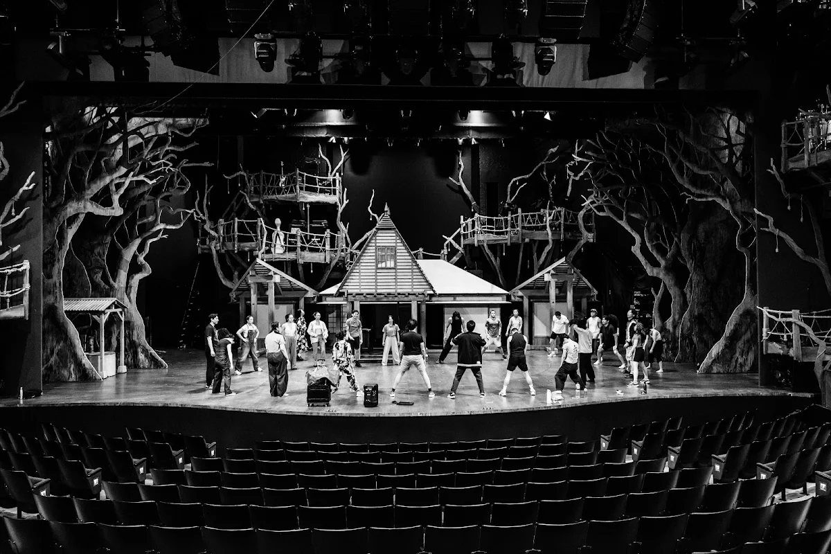 Black and white photograph of the company on the forest set, seen from the back of an empty auditorium