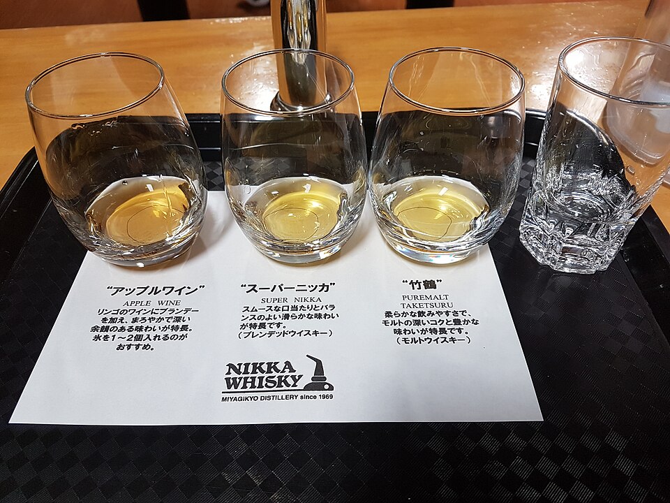Tasting tray at Nikka's Miyagikyo Distillery with three glasses of apple wine, Super Nikka and Taketsuru Pure Malt on a printed card