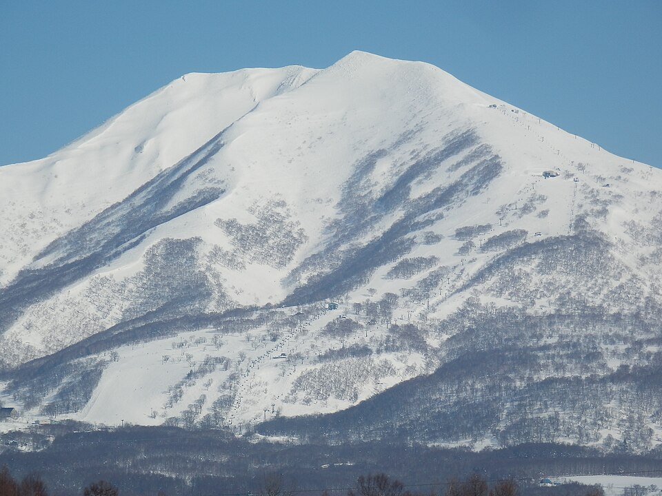 Snow covered Mount Niseko Annupuri in Hokkaido with ski runs cut through the trees on its lower slopes