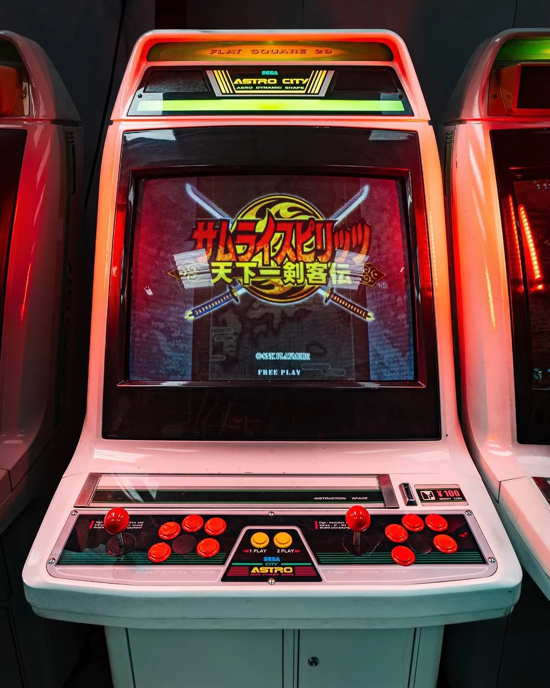 A cream Sega Astro City sit-down arcade cabinet with a red joystick and button panel, its screen showing a Japanese fighting game title