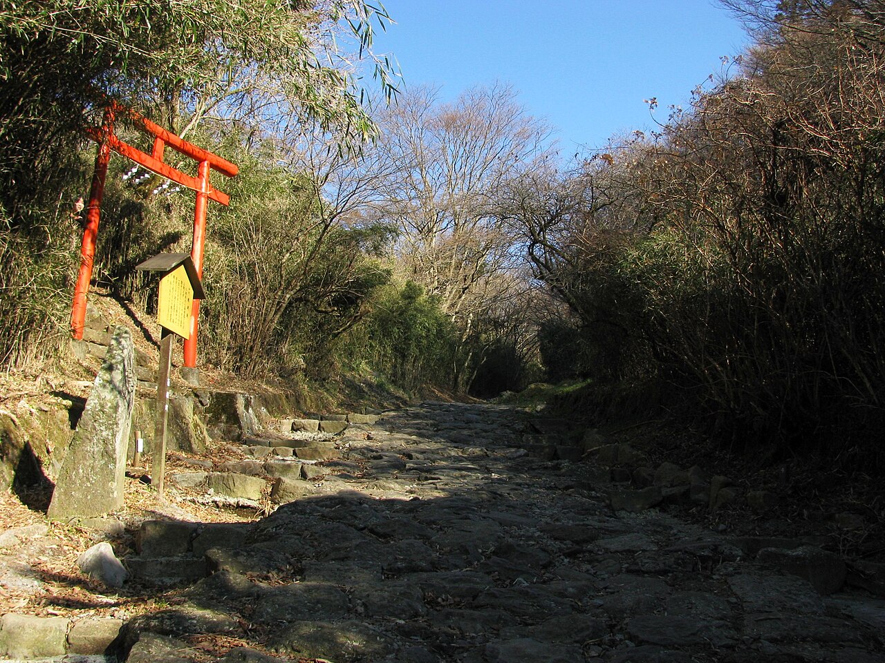 Cobbled stone slope of the Old Tōkaidō road in Hakone beside a small red torii gate