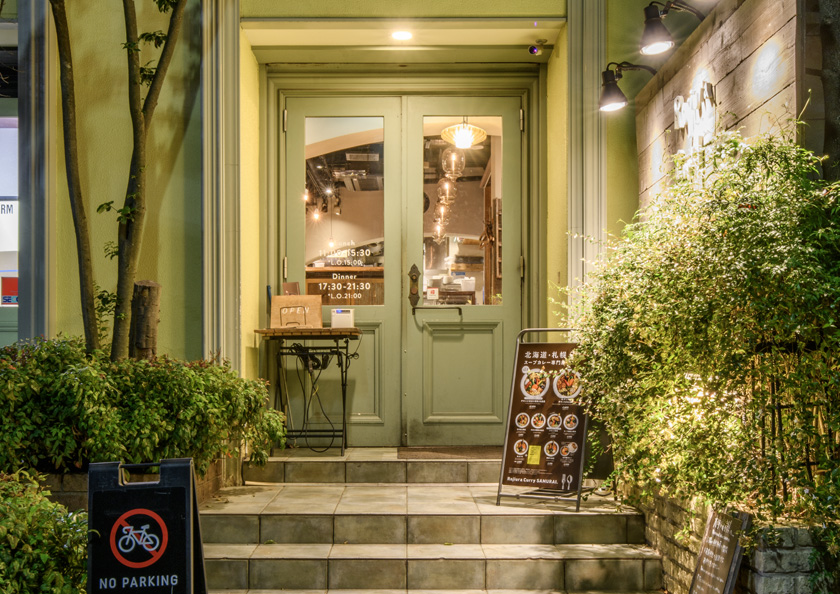 Green double doors and plants at the entrance of Rojiura Curry Samurai Shimokitazawa