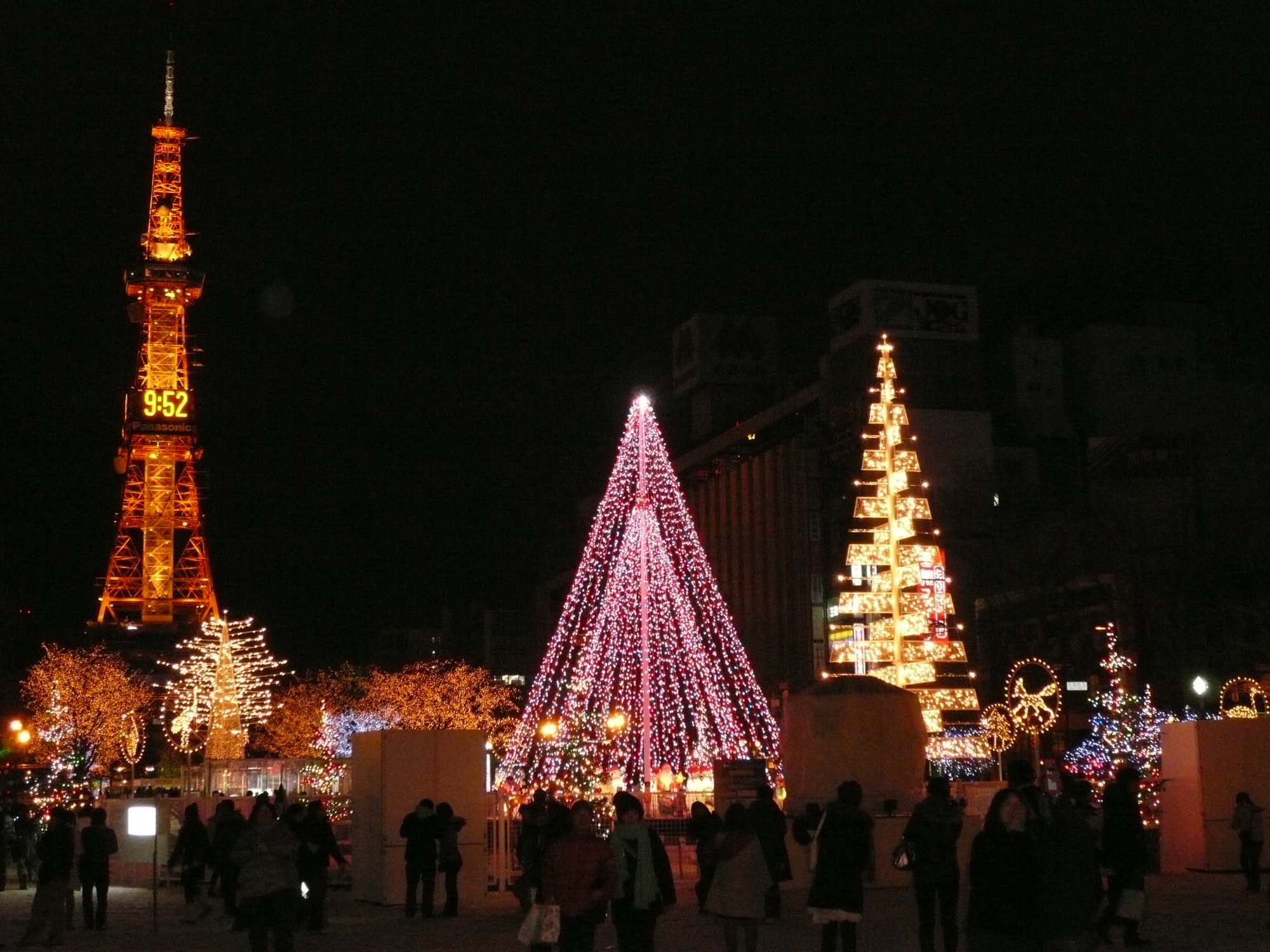 Sapporo White Illumination in Ōdōri Park at night, with lit Christmas tree sculptures in front of the illuminated Sapporo TV Tower