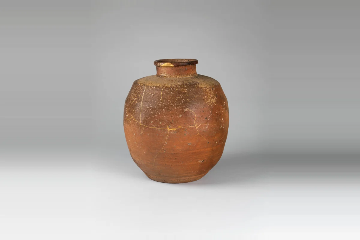 A small orange-brown stoneware tea jar with a narrow neck, its body crossed by fine lines of gold lacquer where old cracks were mended