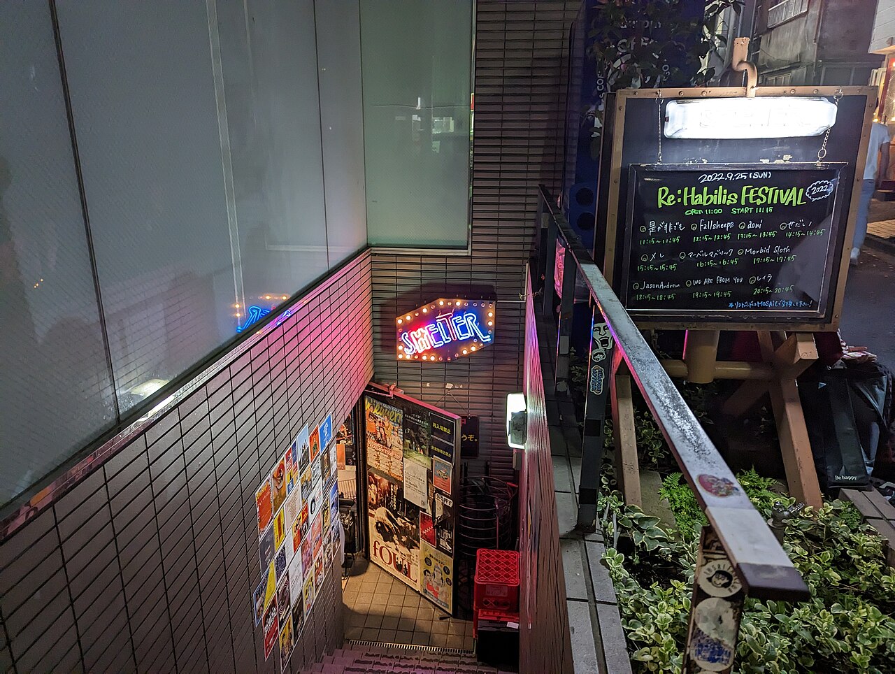 Stairs leading down to the Shelter live house in Shimokitazawa, with its neon sign and a gig board outside