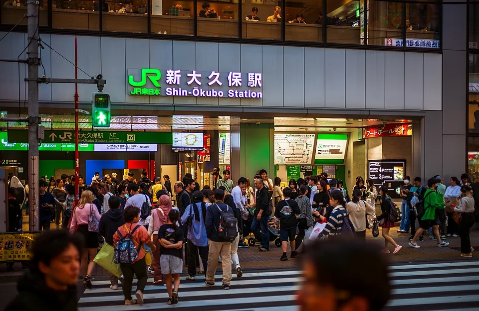 Crowds crossing Okubo-dori outside the entrance of JR Shin-Okubo Station in Shinjuku