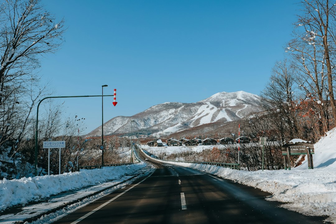 Cleared road between snowbanks leading towards the Niseko Hirafu ski slopes on a clear winter day