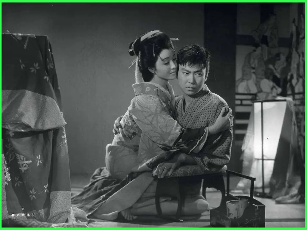 Black and white still from Sun in the Last Days of the Shogunate (1957): a woman in an elaborate kimono and hairstyle holds a young man in an Edo period room