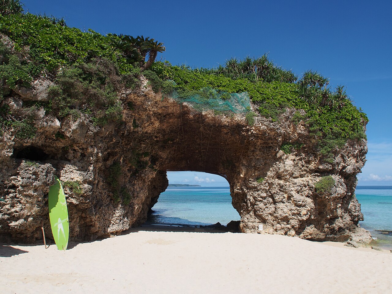 The limestone rock arch on the white sand of Sunayama Beach, Miyakojima, with turquoise sea visible through the opening