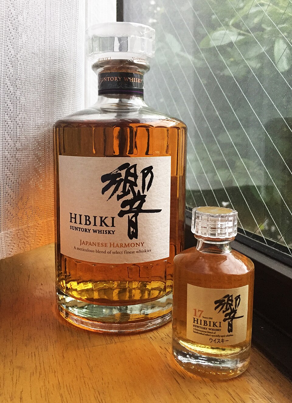A full size bottle of Suntory Hibiki Japanese Harmony next to a miniature Hibiki 17 year old