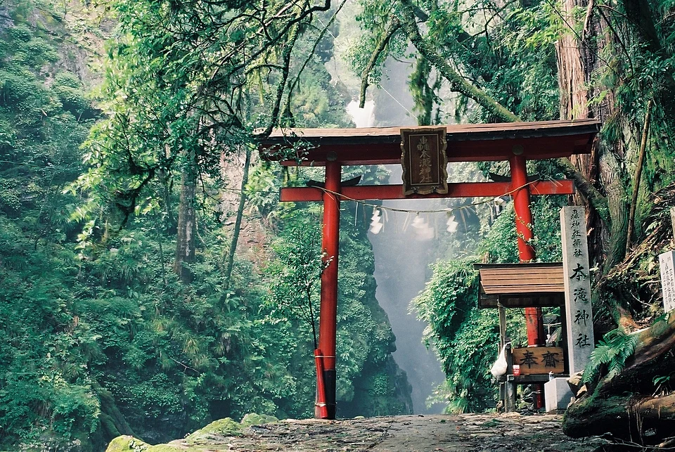 Red torii gate of Todoroki Shrine framing Todoroki Hontaki waterfall in a forested gorge in Kaiyo, Tokushima