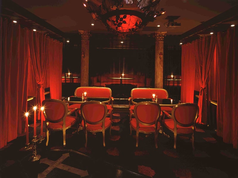 Red velvet curtains, red chairs and candlelit tables in the dining room at Vampire Cafe Ginza
