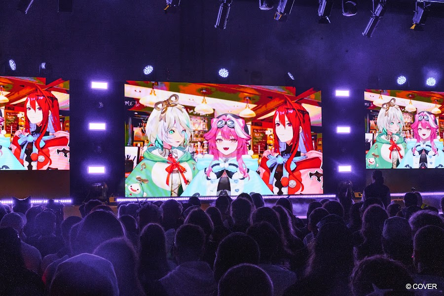 Three hololive English avatars on large screens above a darkened audience on the Monarch Stage at VeXpo 2026