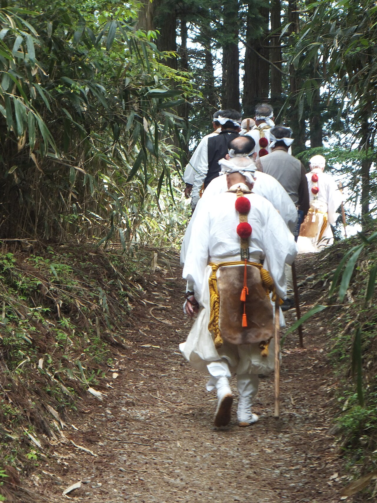 Yamabushi in white robes walking a forest path on the Omine Okugakemichi near Yoshino